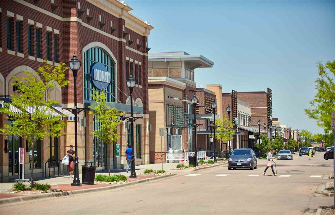 Downtown Centennial CO near Streets at SouthGlenn on a sunny day, with shoppers and parked cars