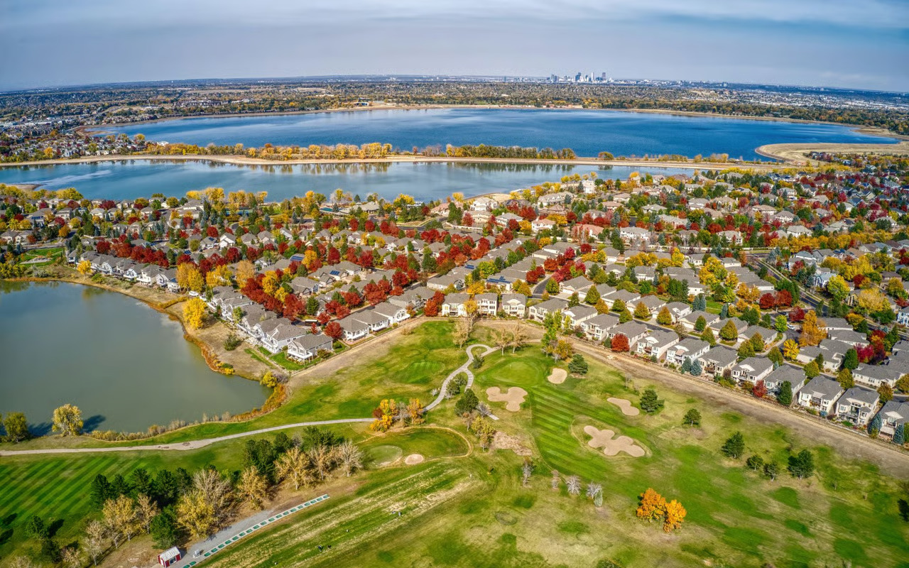 Aerial view of Lakewood, Colorado homes near water and golf course during fall.