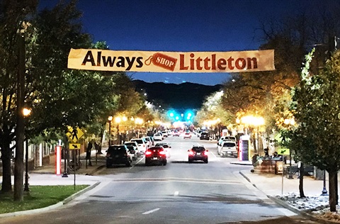 Downtown Littleton street scene at night with “Always Shop Littleton” banner hanging over the road